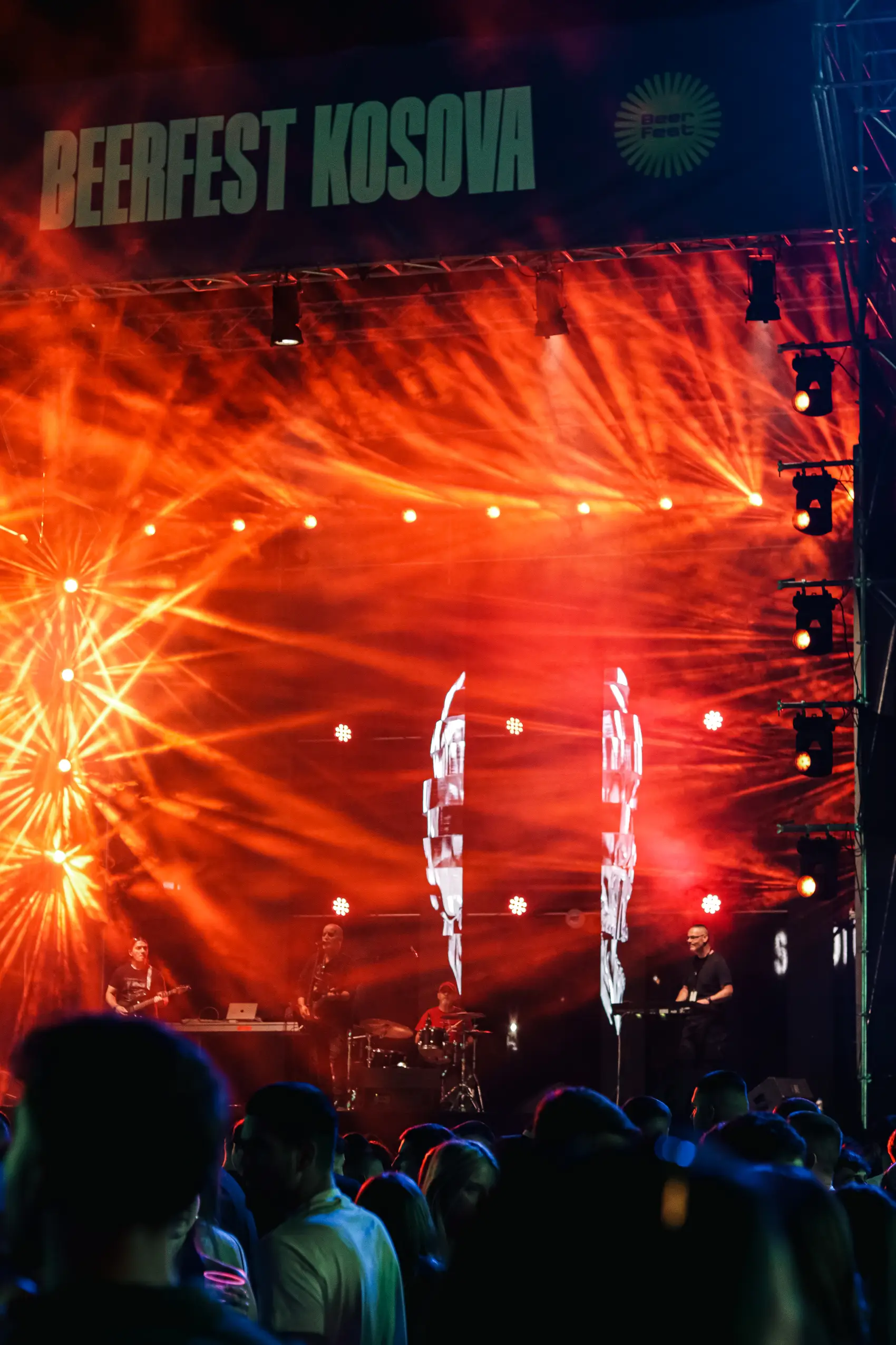 Pyrotechnics and red laser beams erupting over a festival crowd