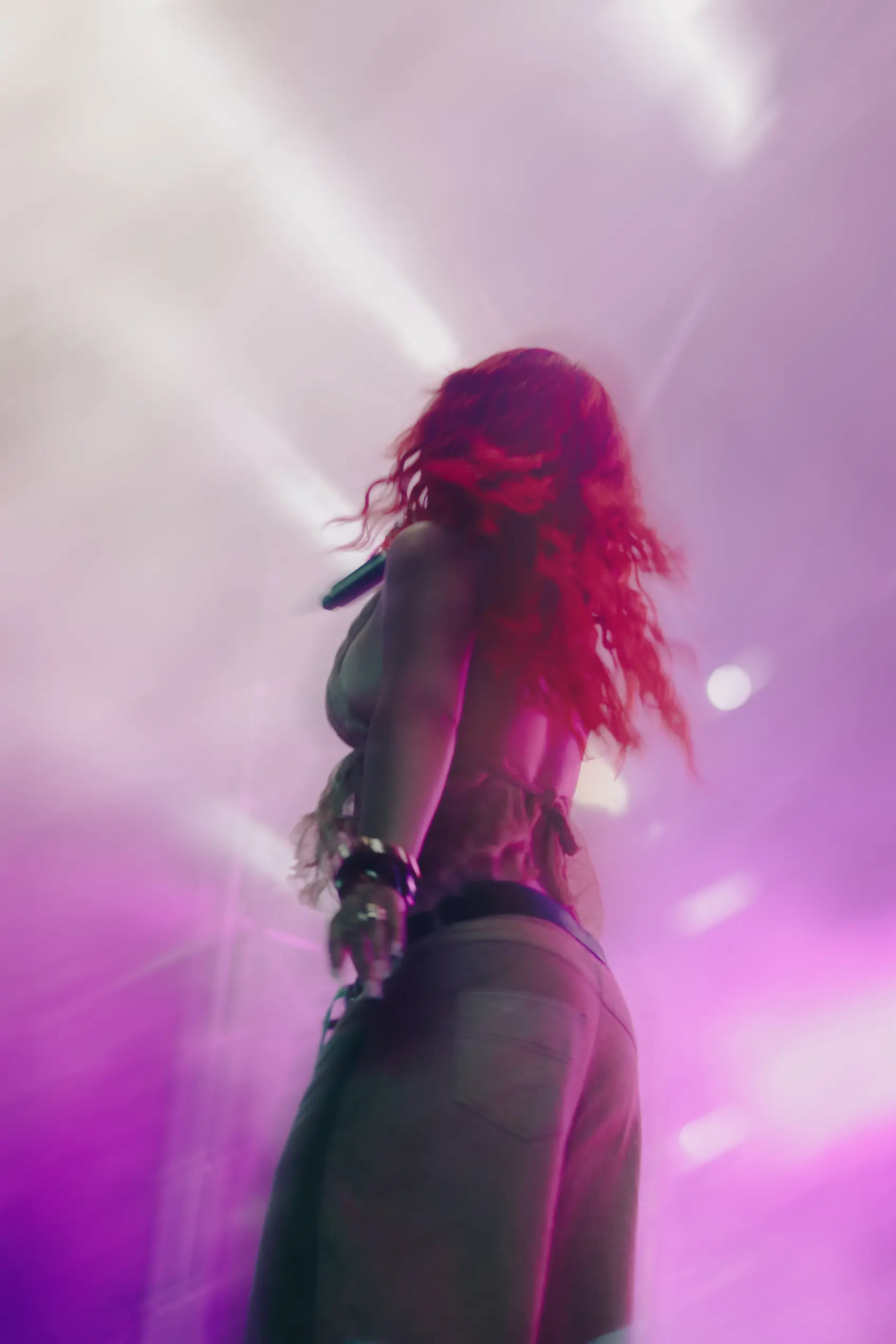 Silhouette of a performer facing a sea of pink and purple stage light