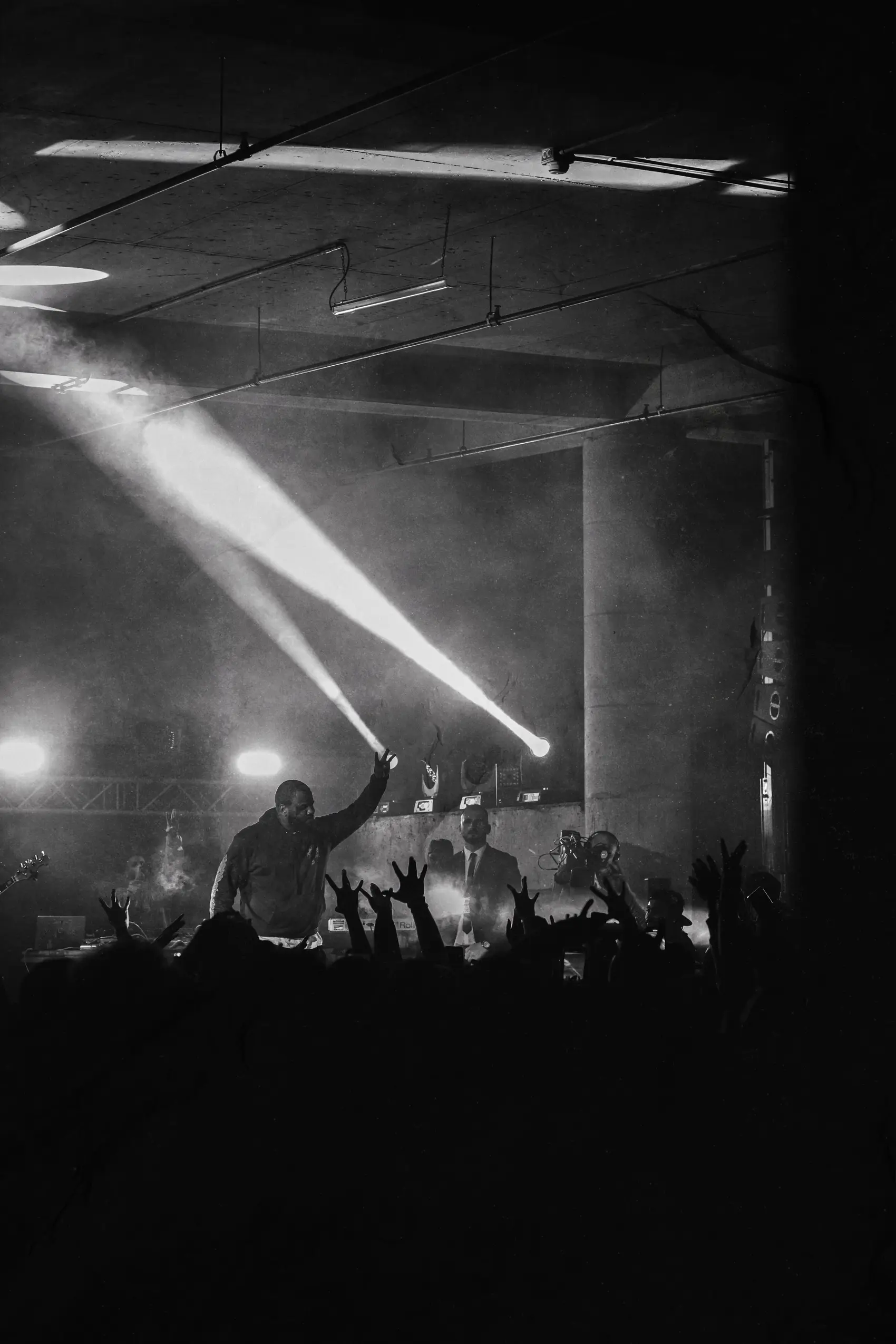 Beams of light cutting through fog above a black and white crowd