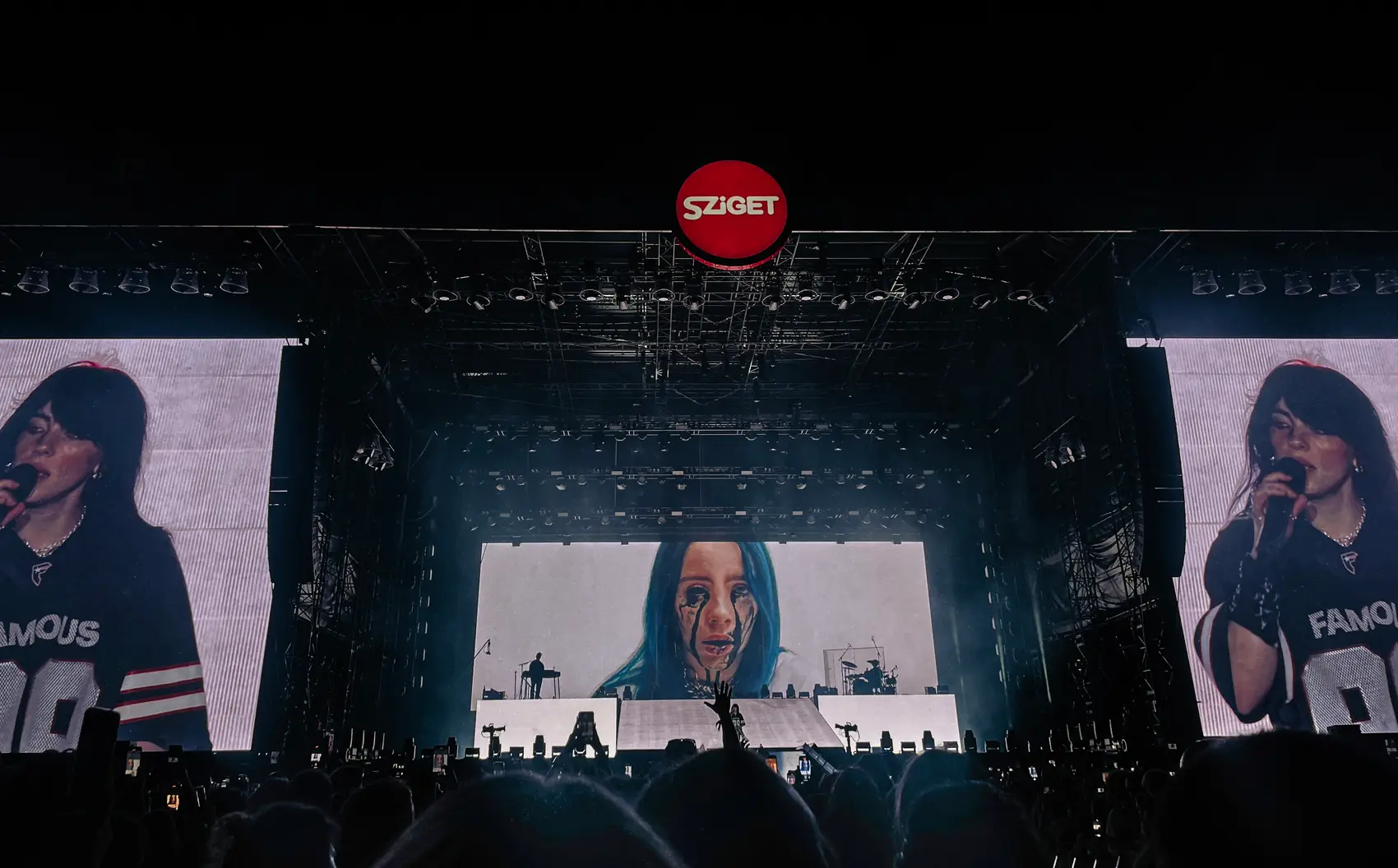 Headliner on a giant screen above a vast festival crowd at night
