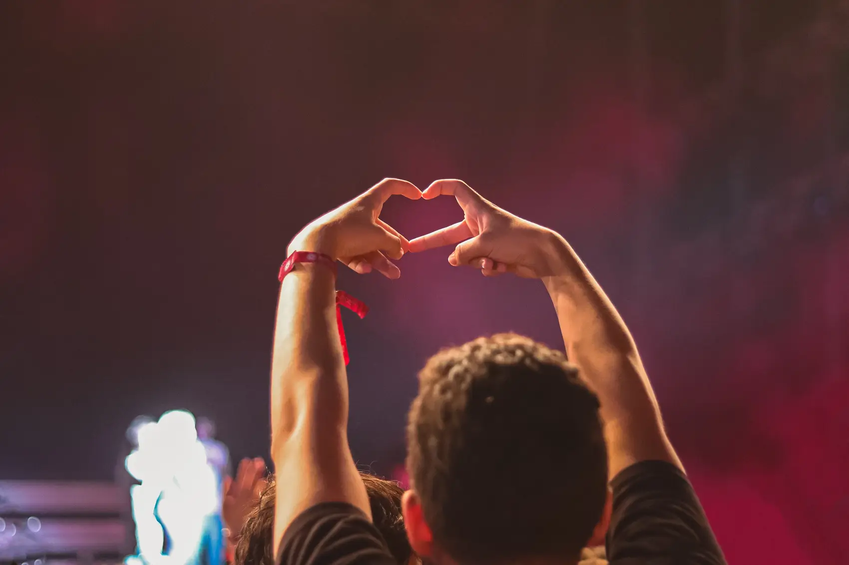 A pair of hands forming a heart against the glow of the stage